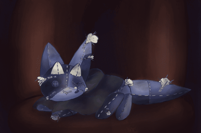 Une poupée abimée de renard bleu foncée, avec une cape noire et deux petites corne blanche. Un de ses "yeux" (des boutons) est en train de tomber.